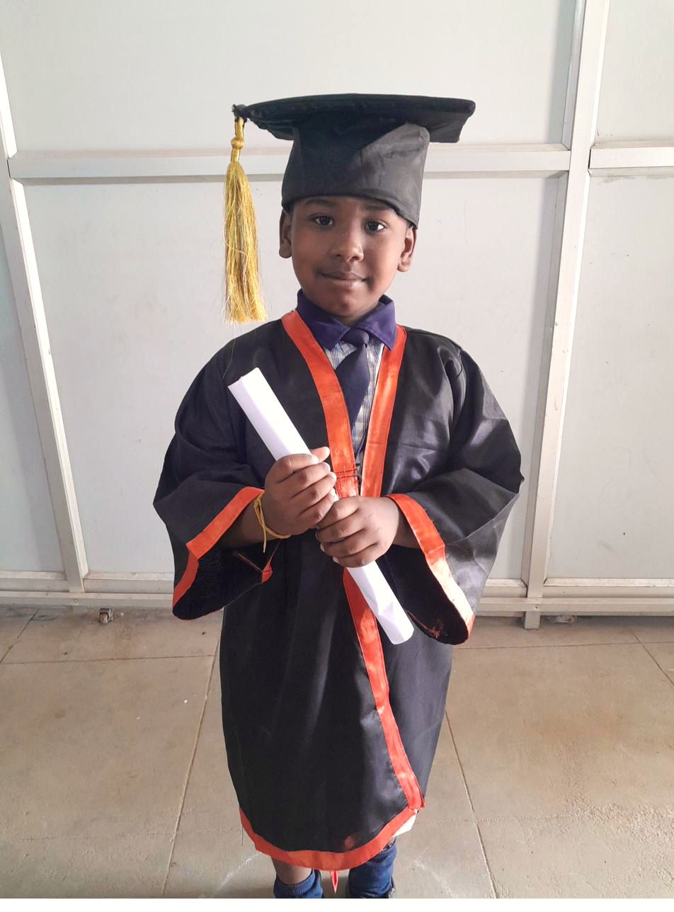 A student in graduation robes holding his Diploma in Computer Science